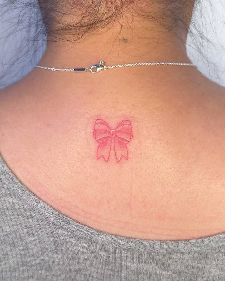 Illustrative style bow tattoo located on the upper back.