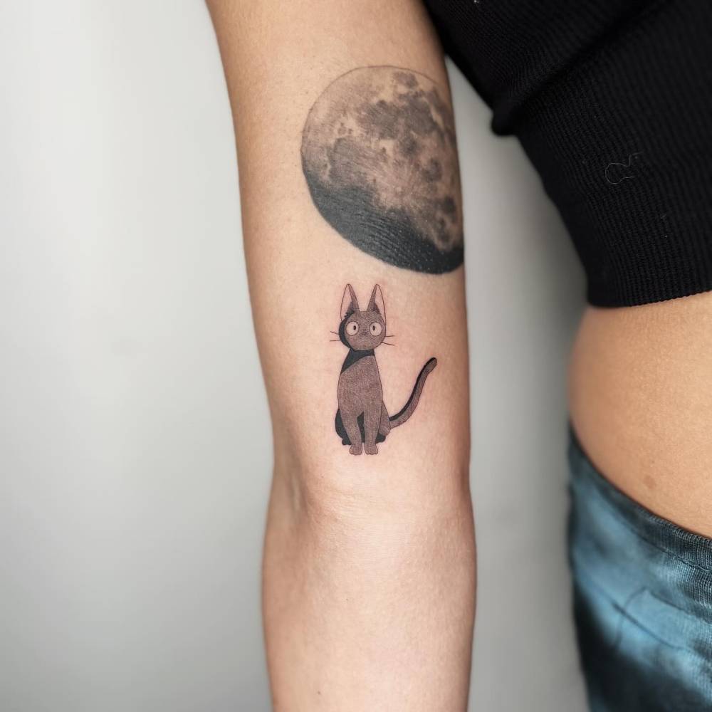 Jiji tattoo located on the inner arm, cartoon style.