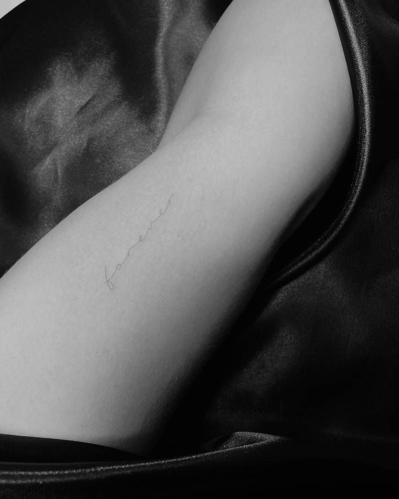 "Forever" lettering tattoo handwritten on the inner arm.