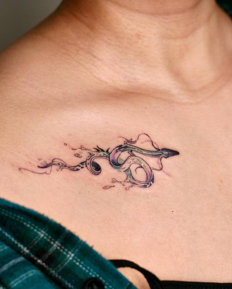 Dragon tattoo located on the collarbone, watercolor style.