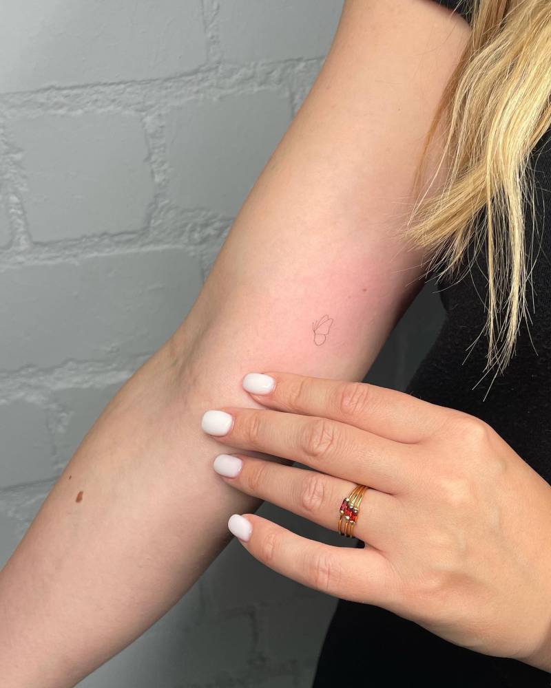 Tiny minimalistic butterfly tattoo located on the inner arm.