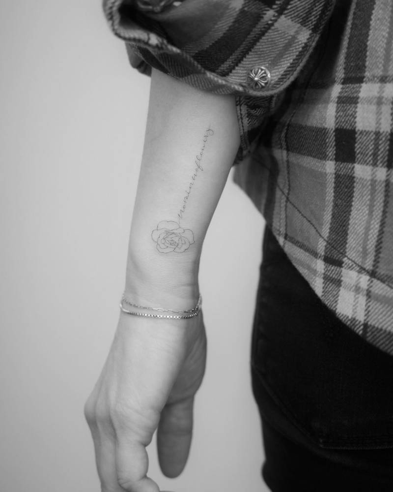 Rose head and "no rain no flowers" tattoo located on the wrist.