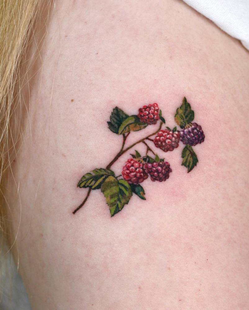 Watercolor style raspberries tattoo located on the shoulder.