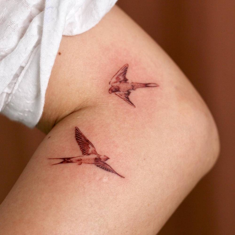 Watercolor style swallows tattoo located on the arm.