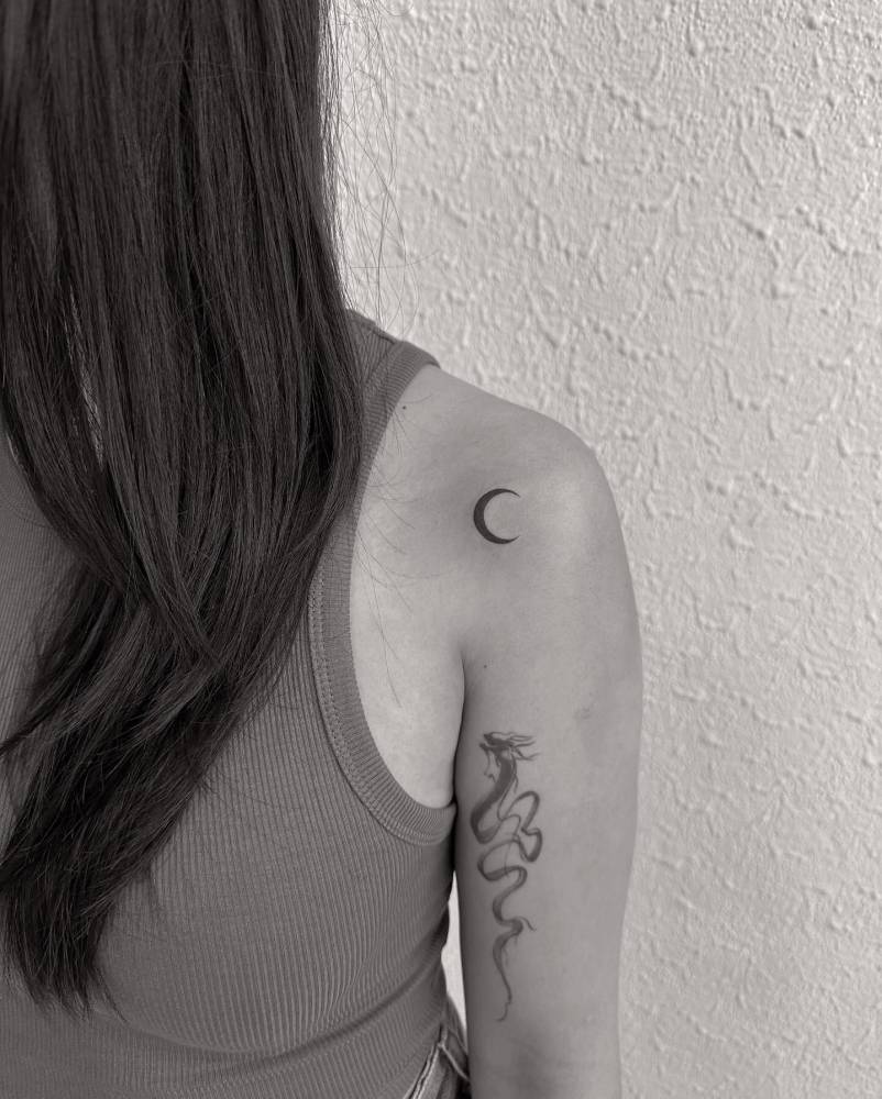 Minimalistic style crescent moon tattoo placed on the shoulder.