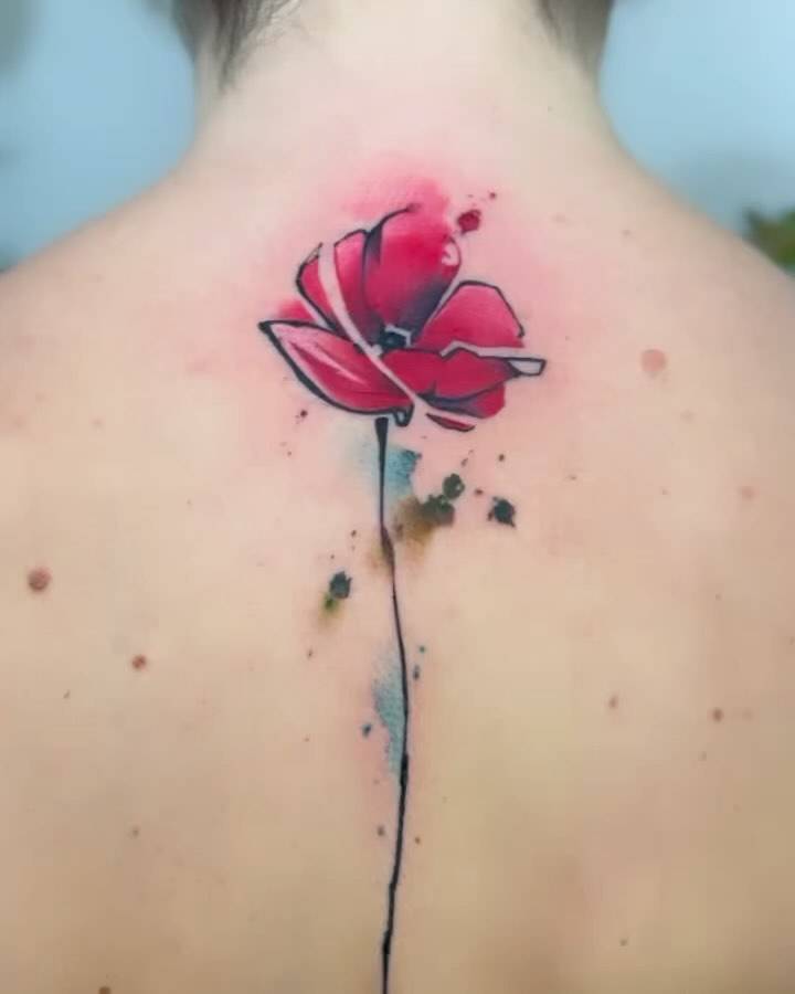 Watercolor style poppy flower tattoo located on the upper back.