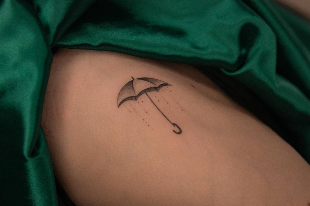 Umbrella tattoo located on the rib, illustrative style.