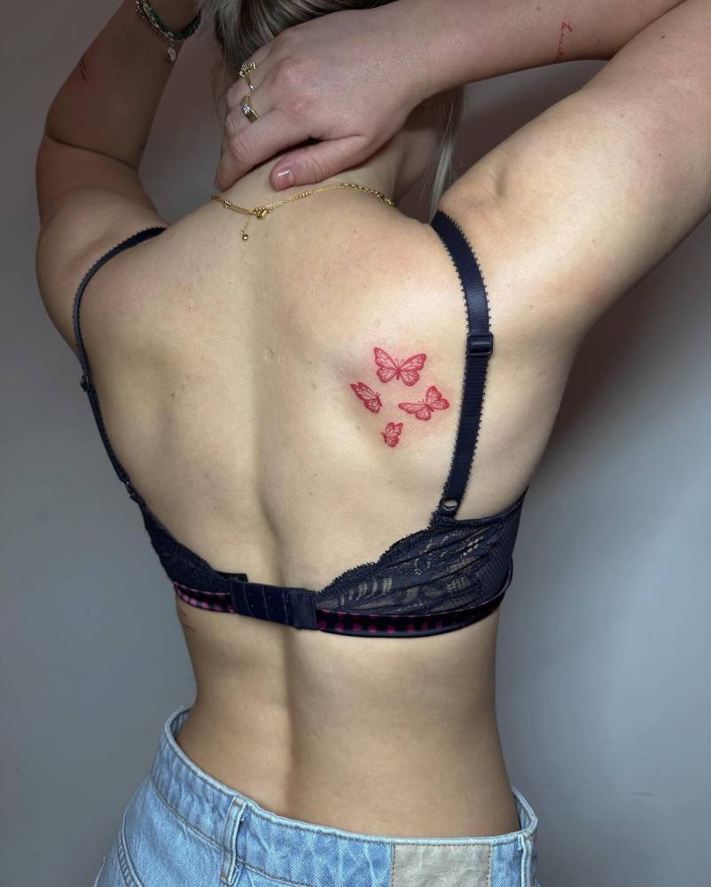 Red butterflies tattoo located on the shoulder blade, illustrative style.