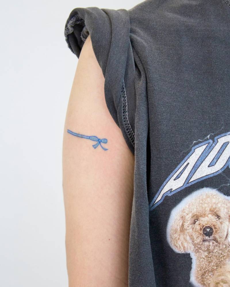 Ribbon tattoo in watercolor style located on the upper arm.