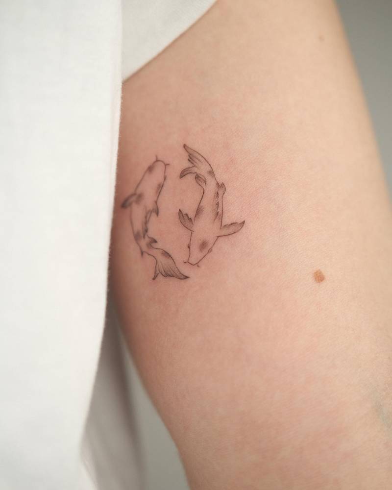 Two opposite fish tattoo located on the inner arm, fine line style.
