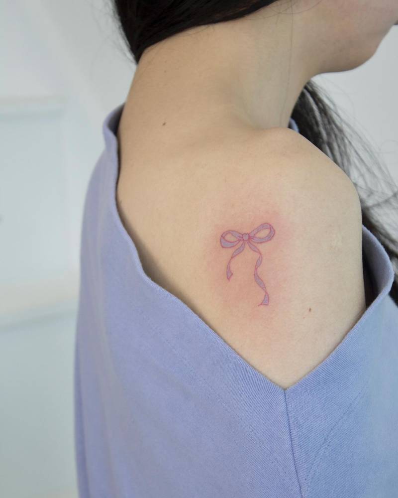 Cute ribbon tattoo located on the shoulder.