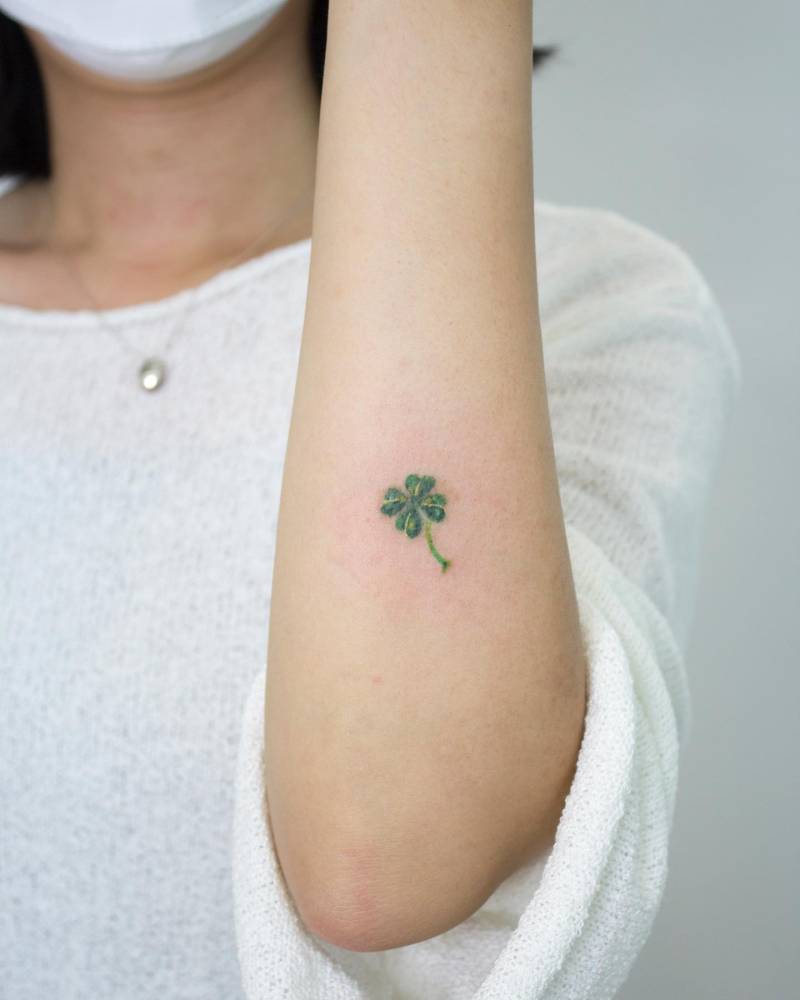 Four leaf clover tattoo in watercolor style located on the forearm.