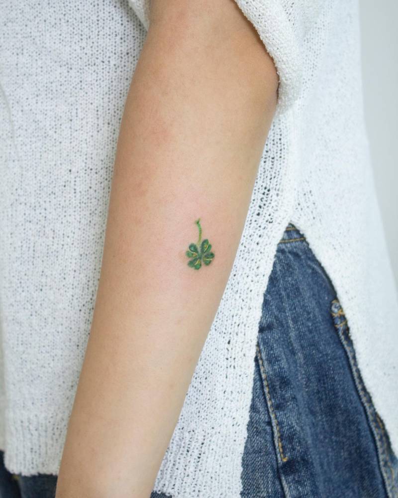 Four leaf clover tattoo in watercolor style located on the forearm.