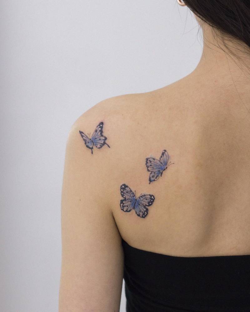 Watercolor style purple butterflies tattoo located on the shoulder blade.