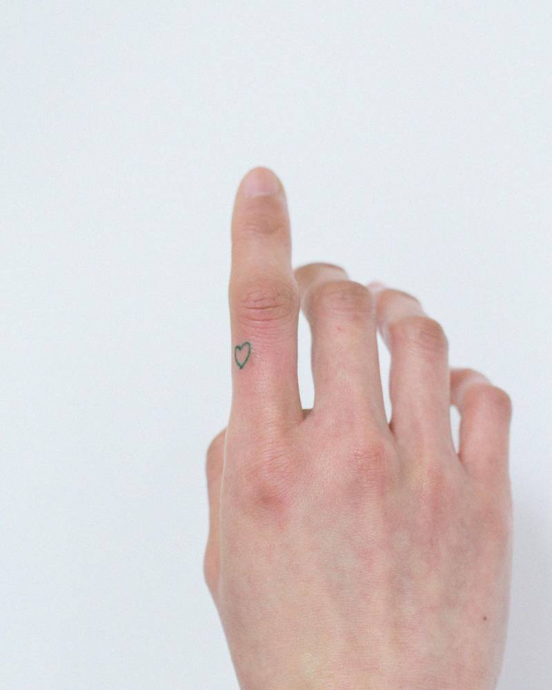 Minimalistic style green heart tattoo done on the finger.