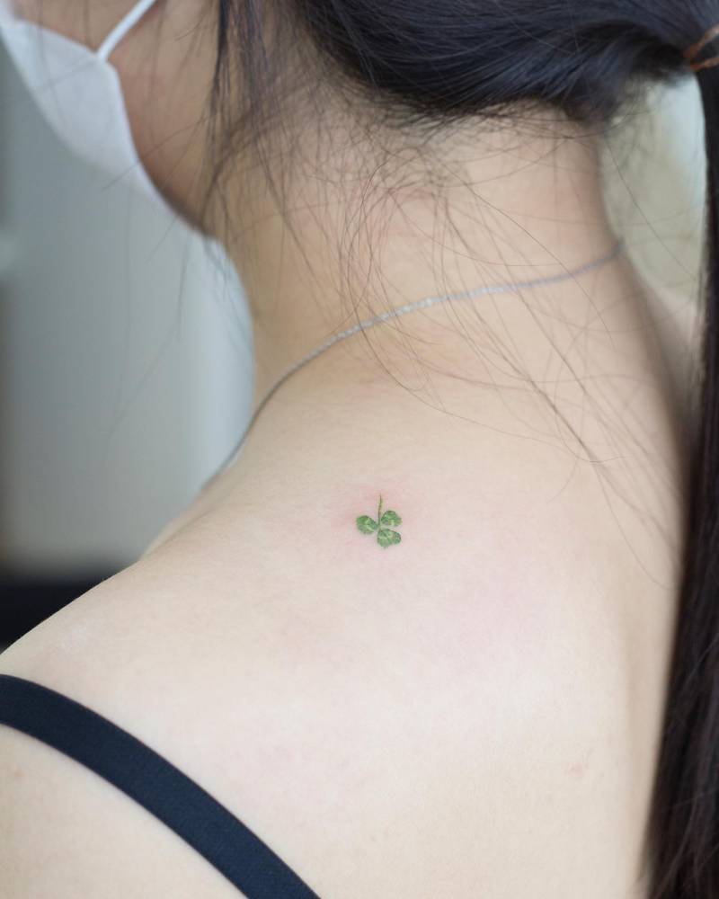 Watercolor style three leaf clover tattoo located on the upper back.