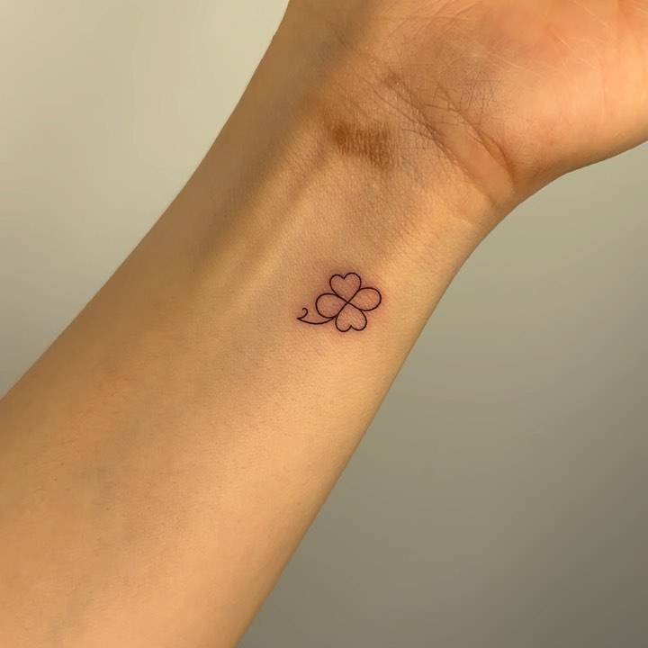 Fine line style four leaf clover tattoo located on the wrist.