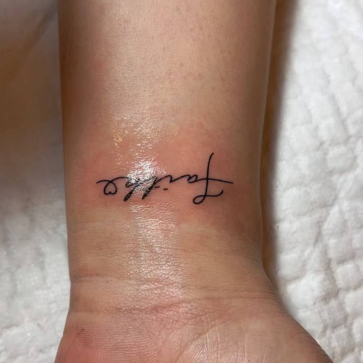 Tattoo of the word "faith" handwritten on the wrist.