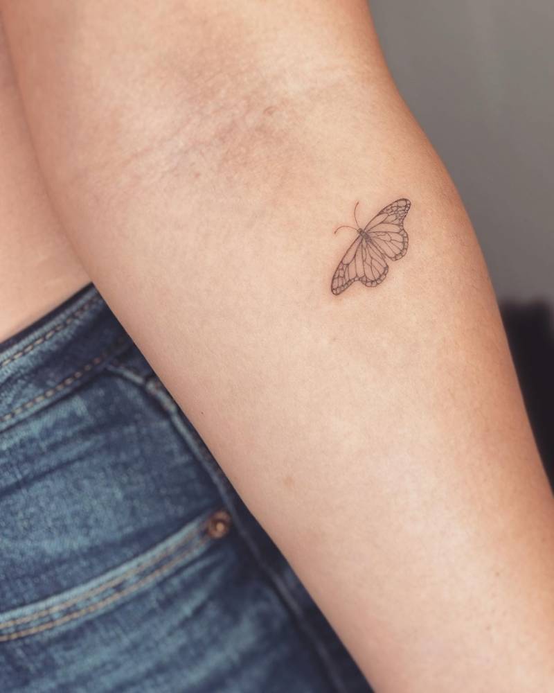 Fine line style butterfly tattoo located on the inner forearm.