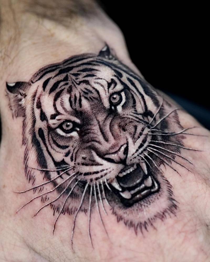 Micro-realistic style tiger head tattoo placed on the hand.