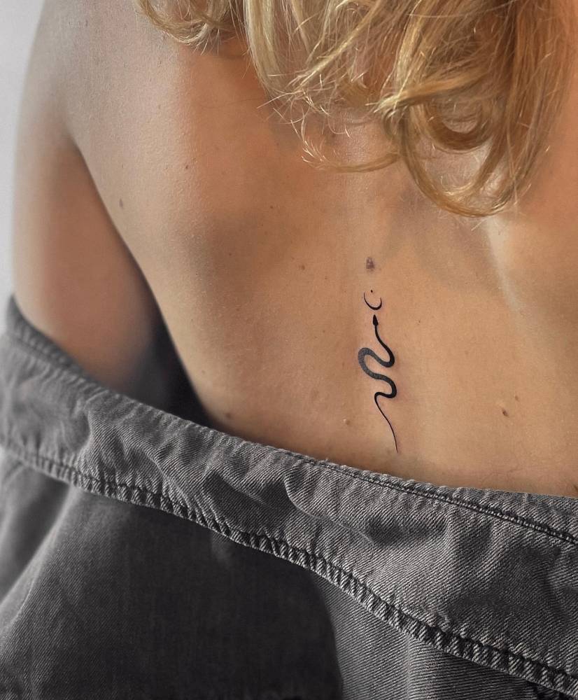 Minimalistic style snake tattoo located on the back.