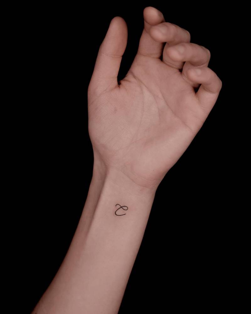 Minimalistic letter "C" tattoo located on the wrist.