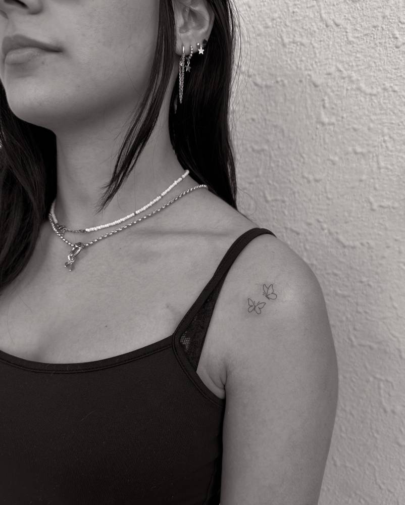 Fine line style butterfly couple tattoo located on the shoulder.