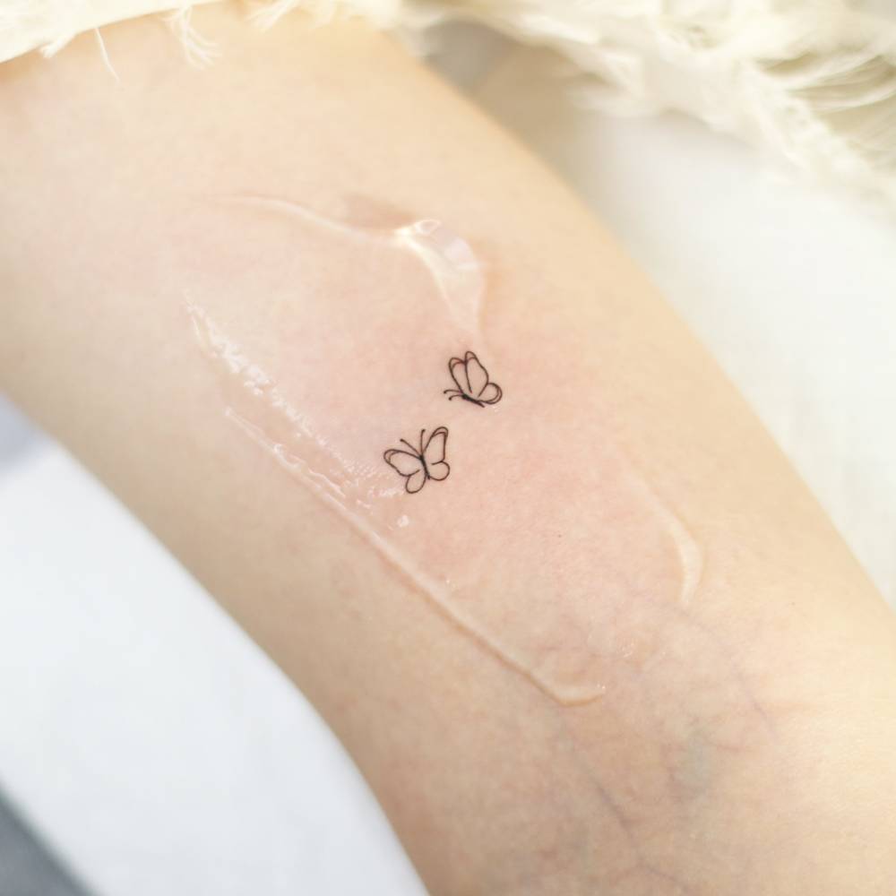 Minimalistic style butterfly couple tattoo placed on the inner arm.