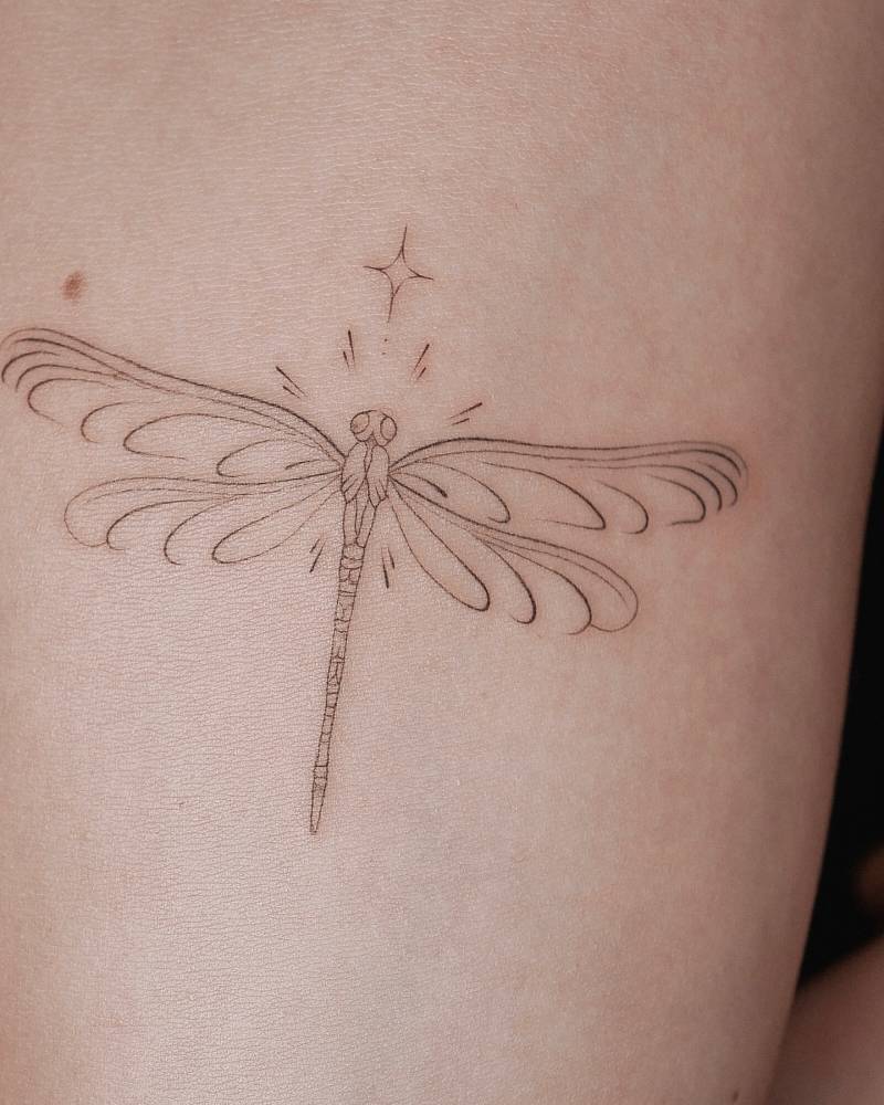 Dragonfly tattoo in fine line style placed on the inner forearm.