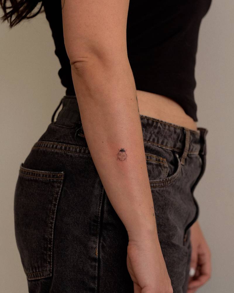 Tiny minimalistic ladybug tattoo located on the forearm.