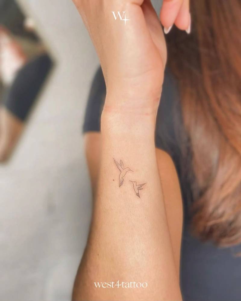 Fine line style hummingbirds tattoo located on the wrist.