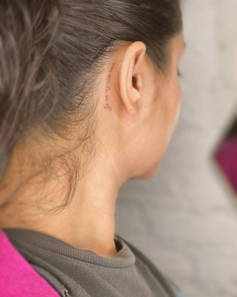 "Je ne regrette rien" lettering tattoo located behind the ear.