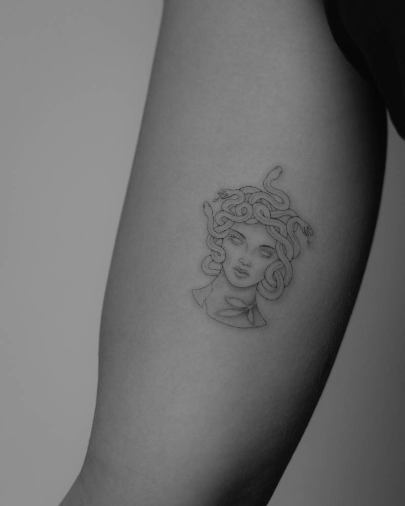 Medusa portrait tattoo in illustrative style located on the inner arm.