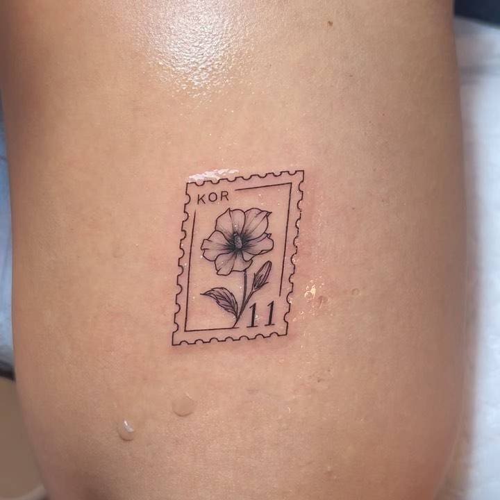 Hibiscus stamp tattoo located on the tricep, illustrative style.