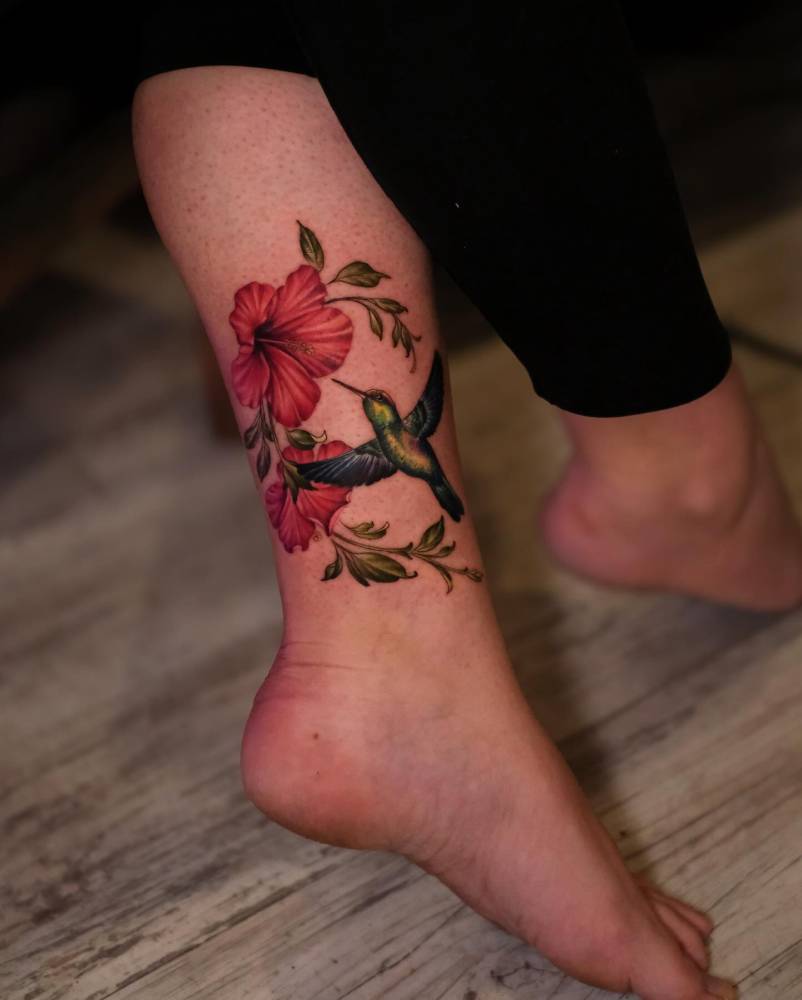 Illustrative style hummingbird and hibiscus tattoo located on the ankle.