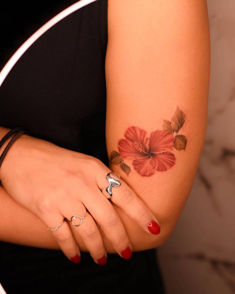 Watercolor style hibiscus tattoo placed on the upper arm.