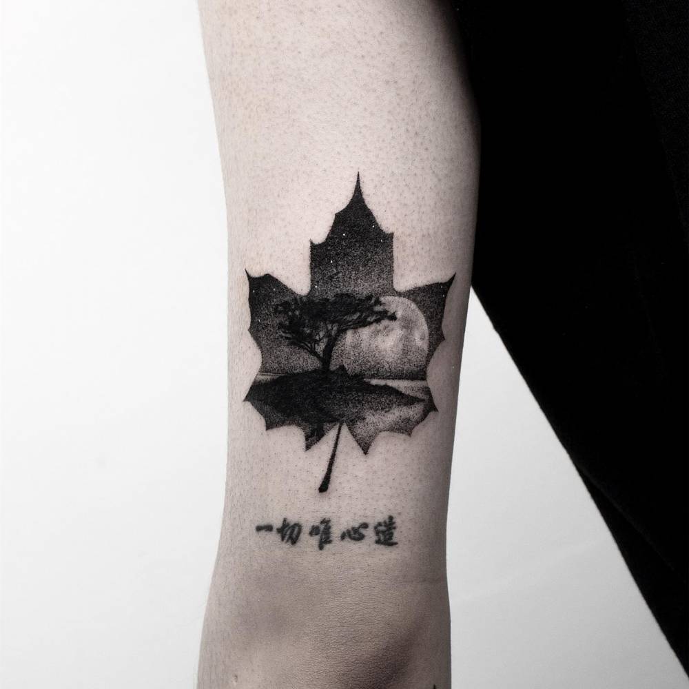 Maple leaf and landscape tattoo located on the tricep.
