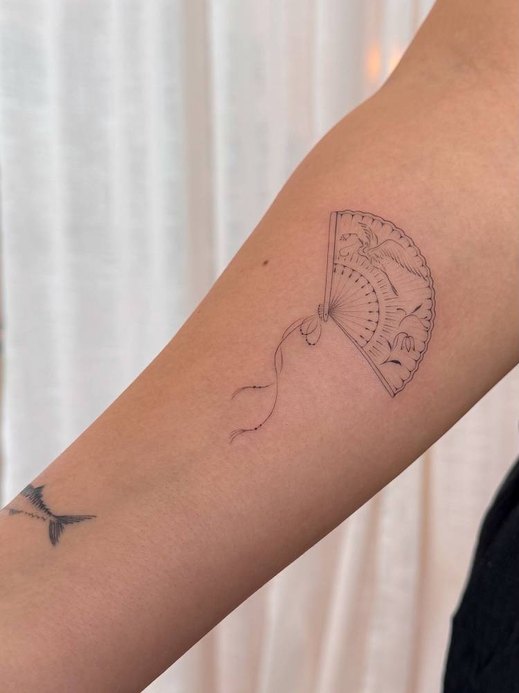 Fine line style hand fan tattoo done on the inner forearm.