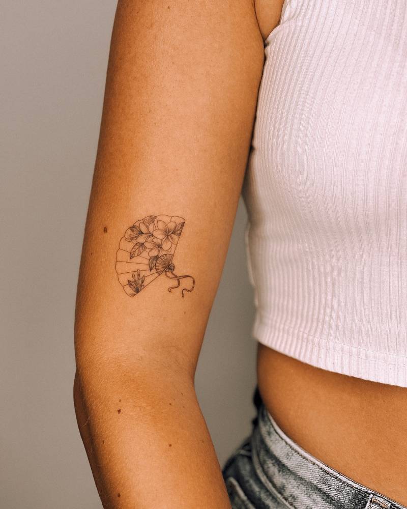 Fine line style hand fan tattoo located on the upper arm.