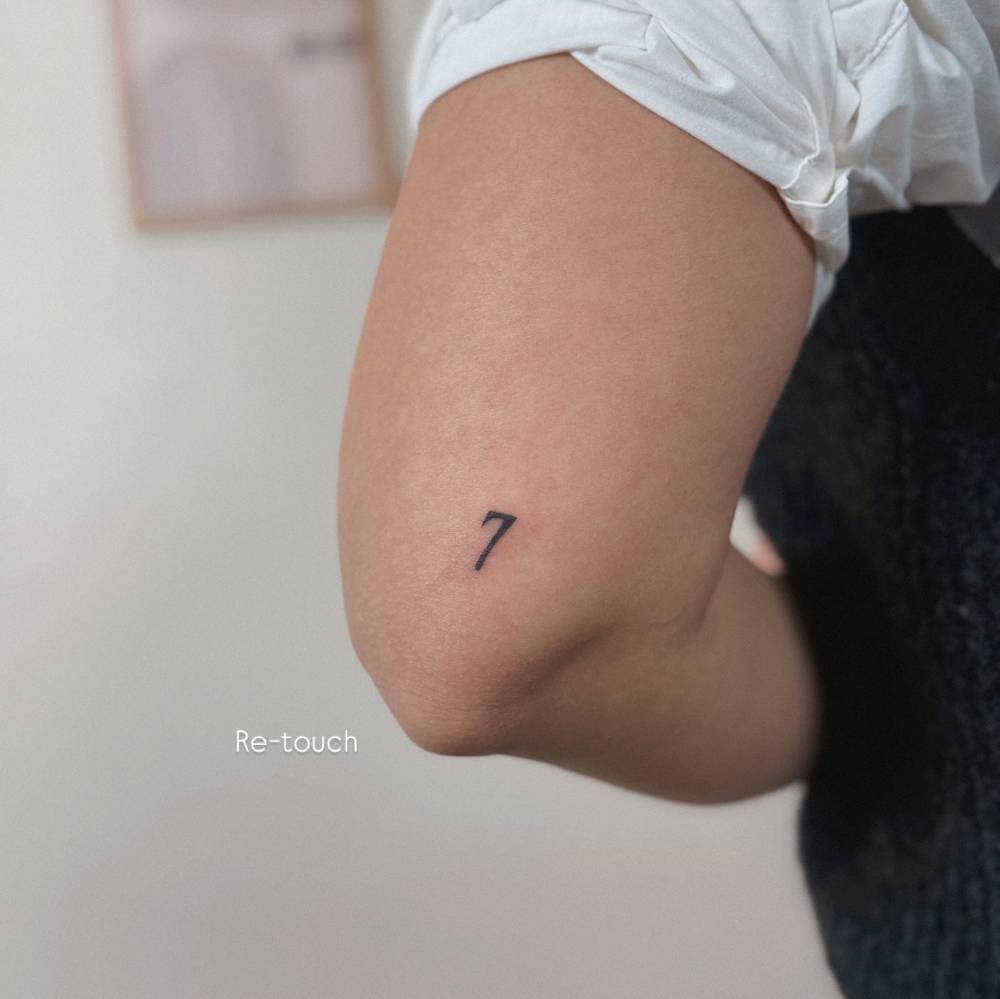 Little tattoo of the number "7" located on the tricep.