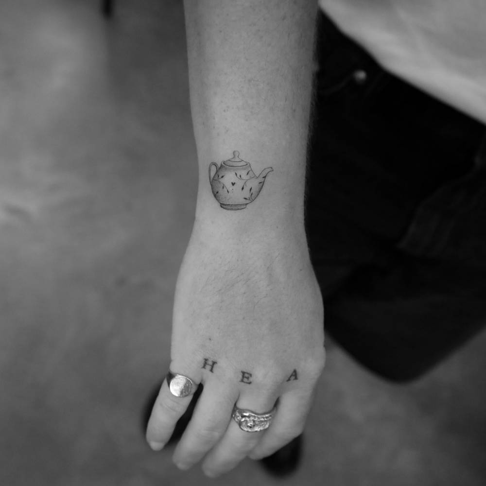 Small illustrative style teapot tattoo located on the wrist.