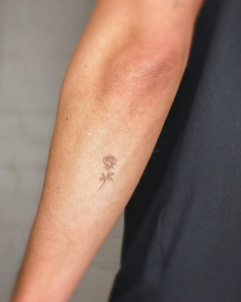 Rose tattoo in minimalistic style located on the forearm.