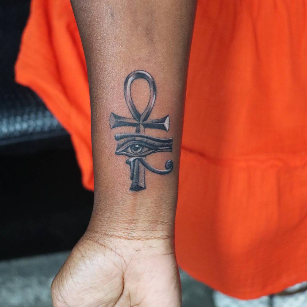 Illustrative style Ankh and Eye of Horus tattoo located on the wrist.