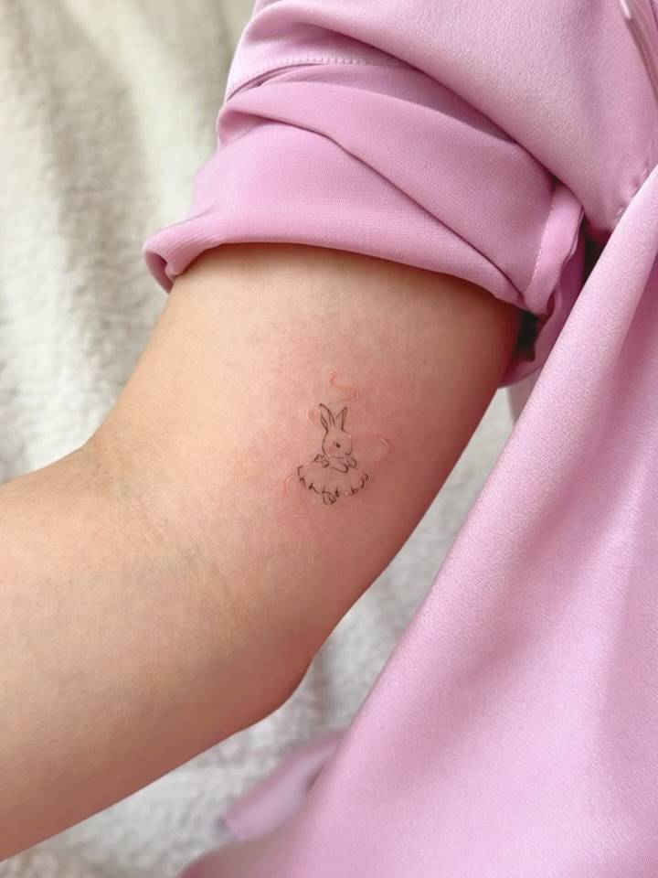 Fine line style ballet dancing rabbit tattoo located on the inner arm.