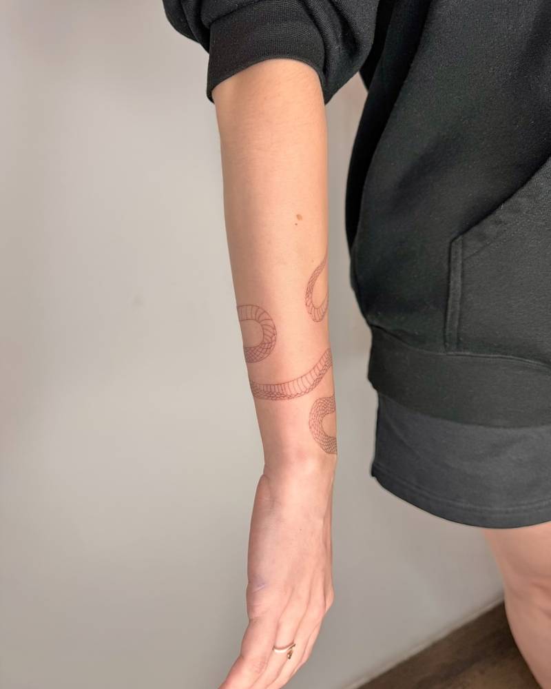 Snake bracelet tattoo in fine line style located on the wrist.