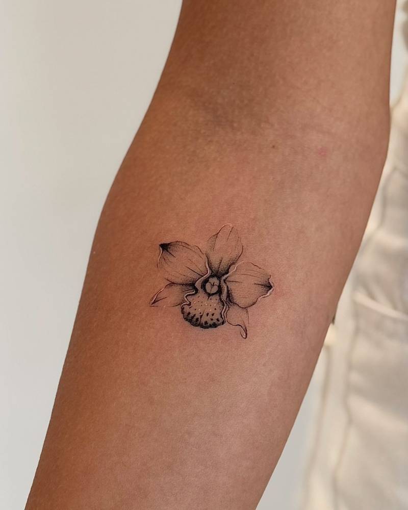 Micro-realistic style orchid tattoo placed on the inner forearm.
