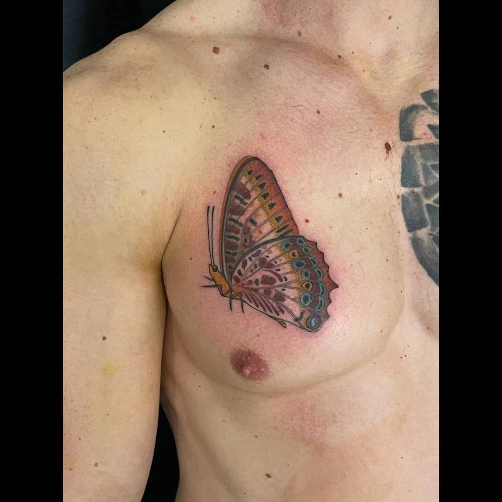 Illustrative style butterfly tattoo located on the chest.