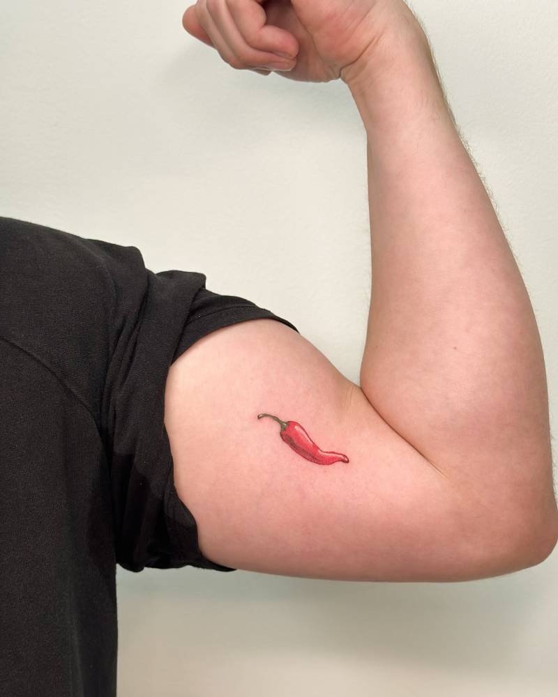Illustrative style red chili tattoo located on the inner arm.