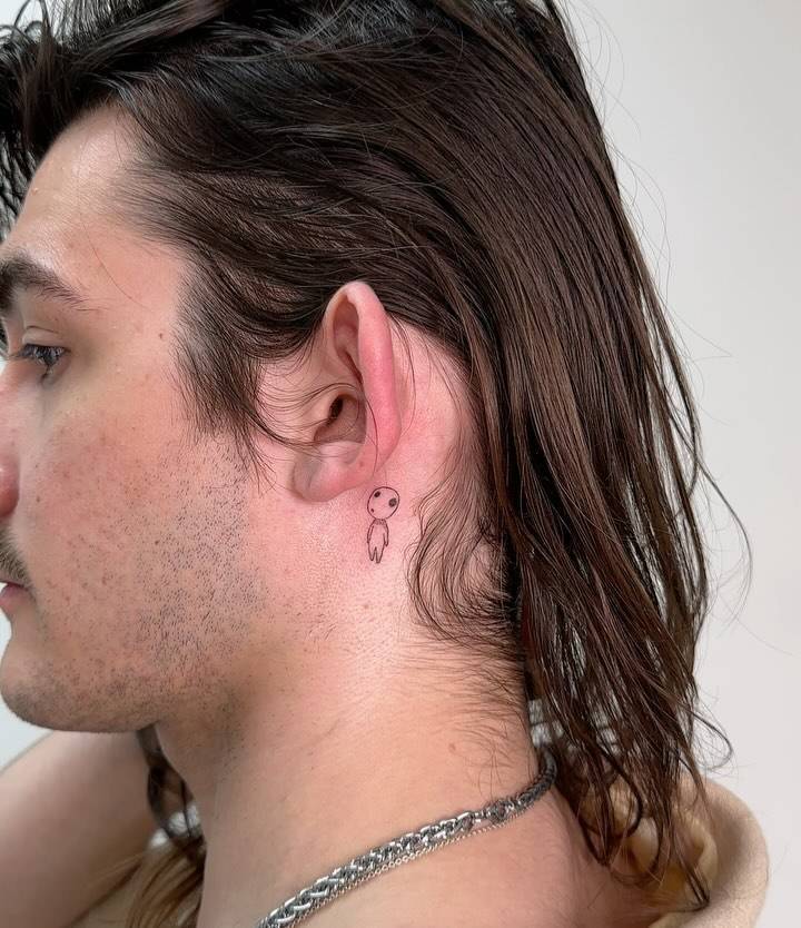 Kodama tattoo in cartoon style located behind the ear.