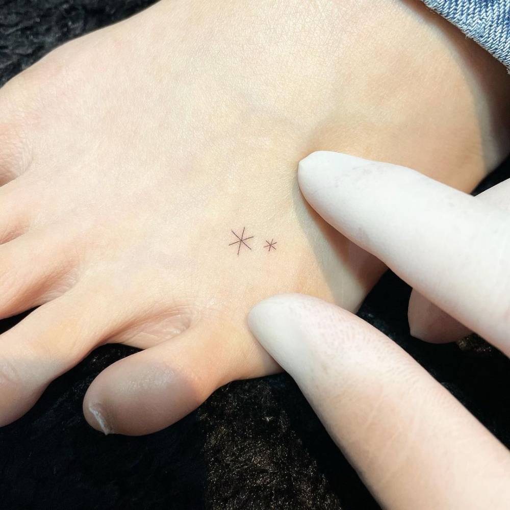 Tiny stars tattoo located on the foot, minimalist style.